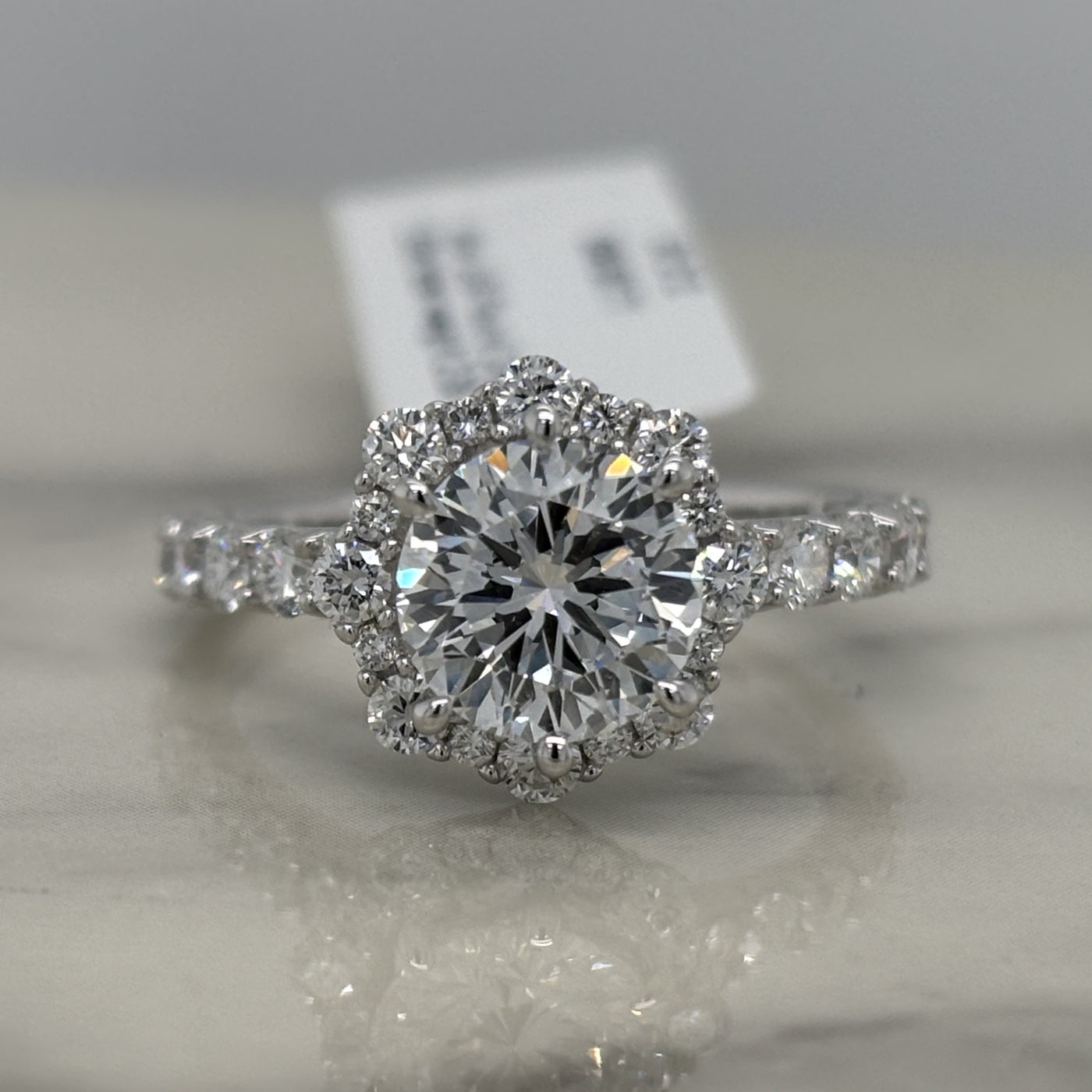 white gold round engagement ring with floral shaped halo and accent diamonds