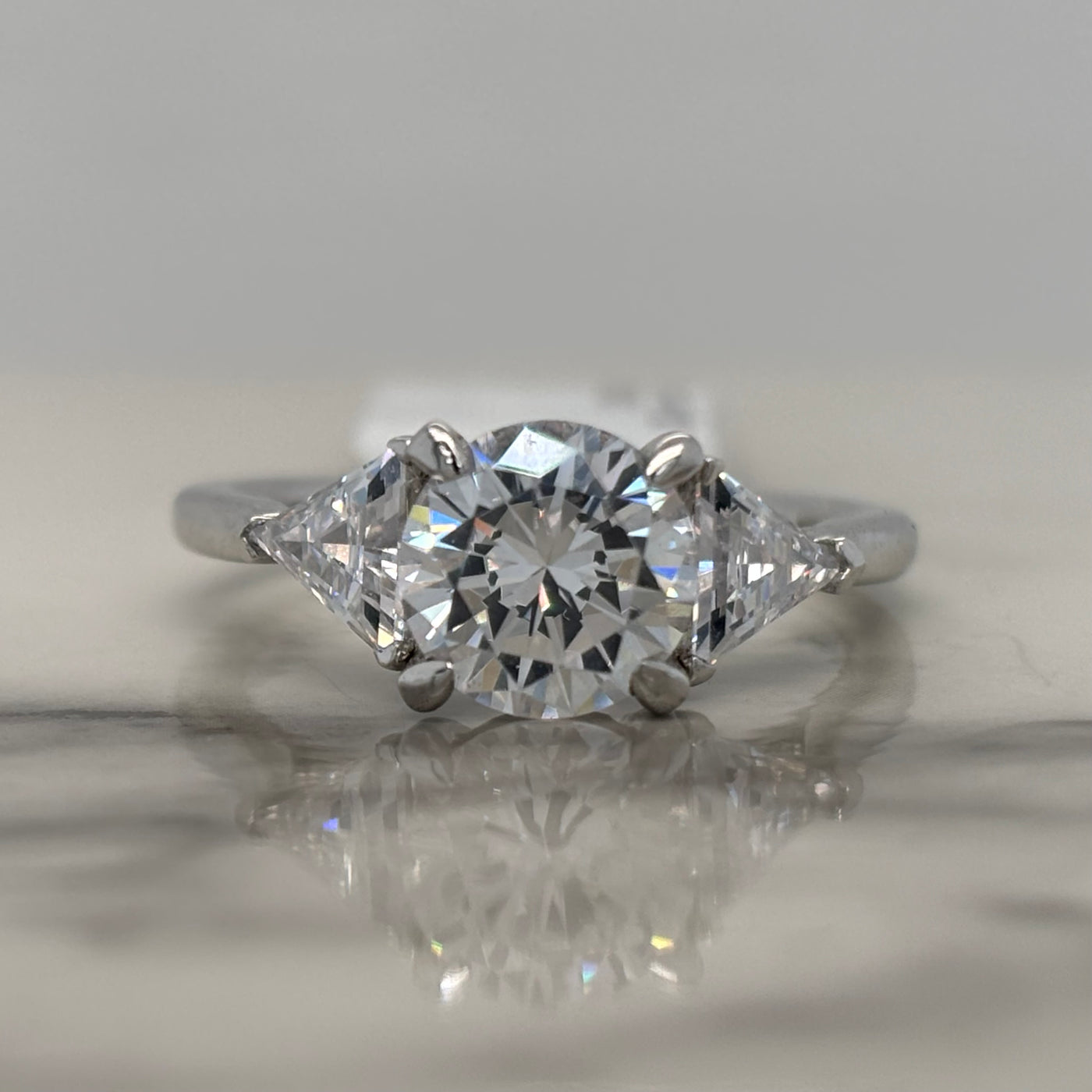 White Gold Round Three Stone Engagement Ring With Trillion Side Stones