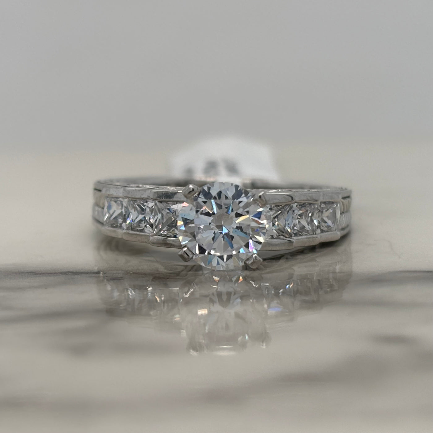 White Gold Round Engagement Ring With Channel Set Princess Cut Side Stones