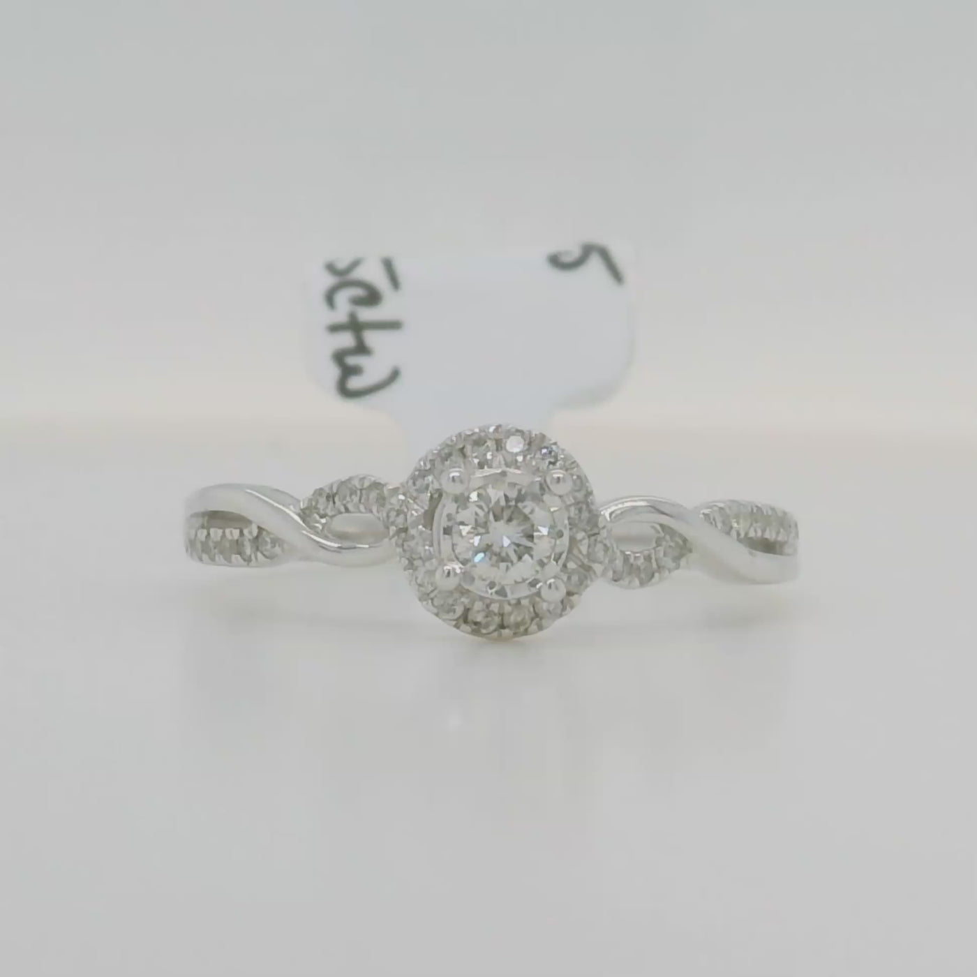 white gold engagement ring with round center stone and halo with accent diamonds and twist design